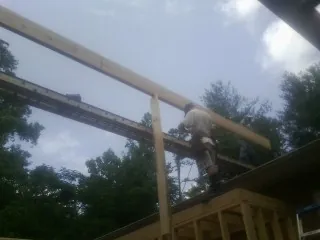 Carpenter setting a ridge beam over a new addition frame — Ice Dam Removal by Roofing Brothers in Oldhams