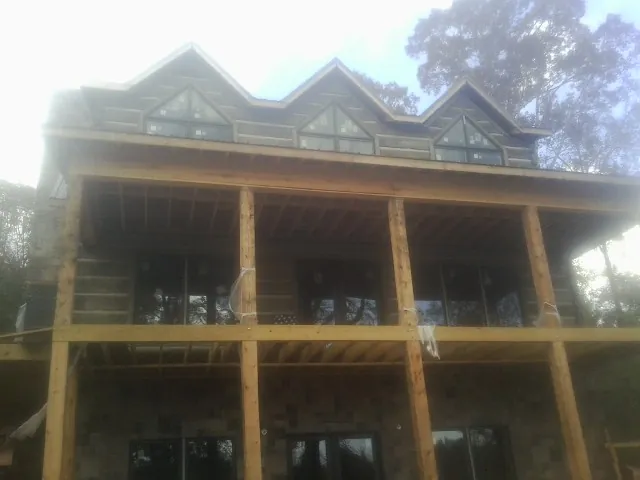 Dormers and porch framing on a large log home under construction — Roof Coating work by our crew in Oldhams