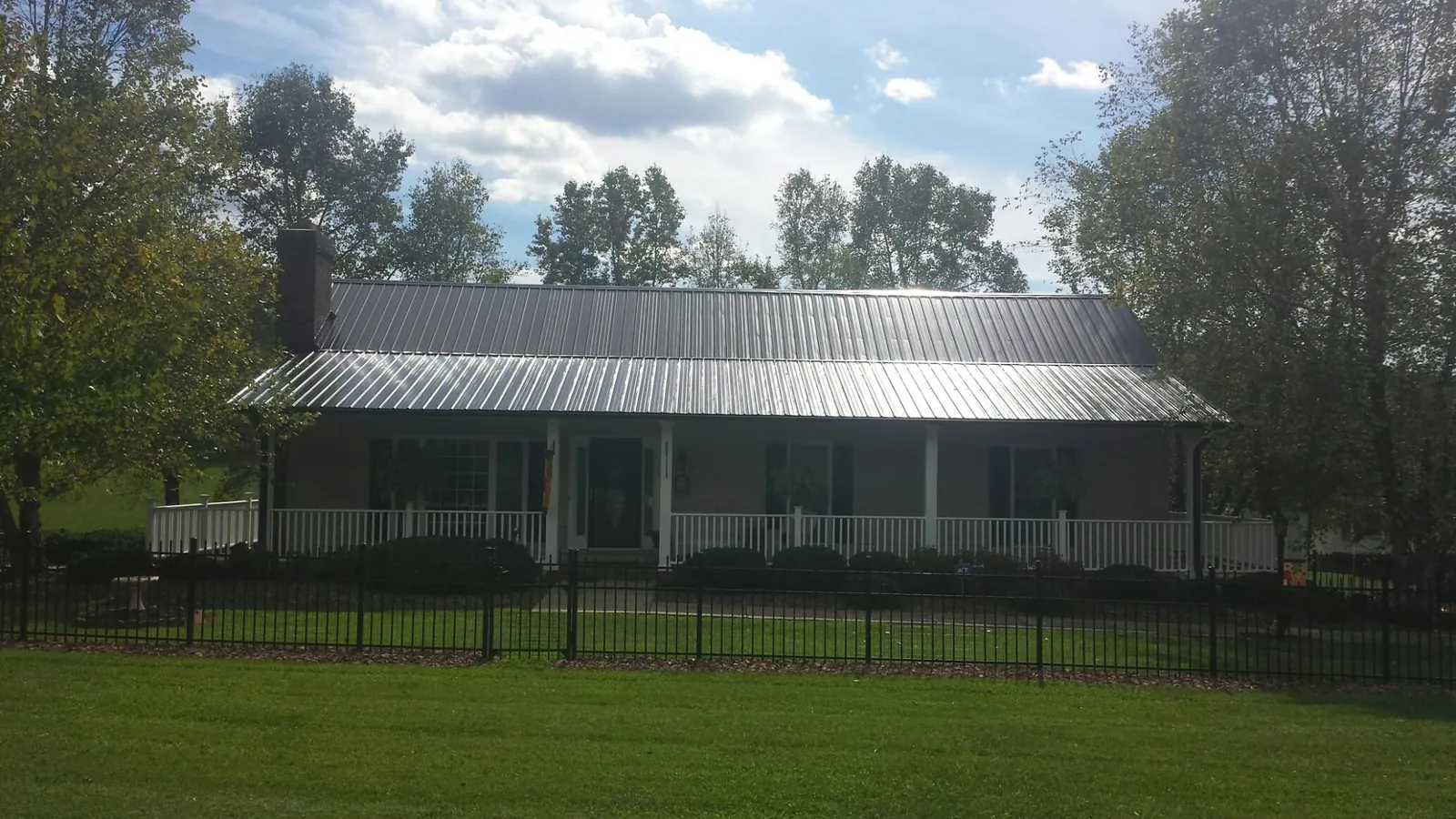 Gray metal roof on a brick ranch with a full width front porch — Gutter Guard Installation work by our crew in Oldhams