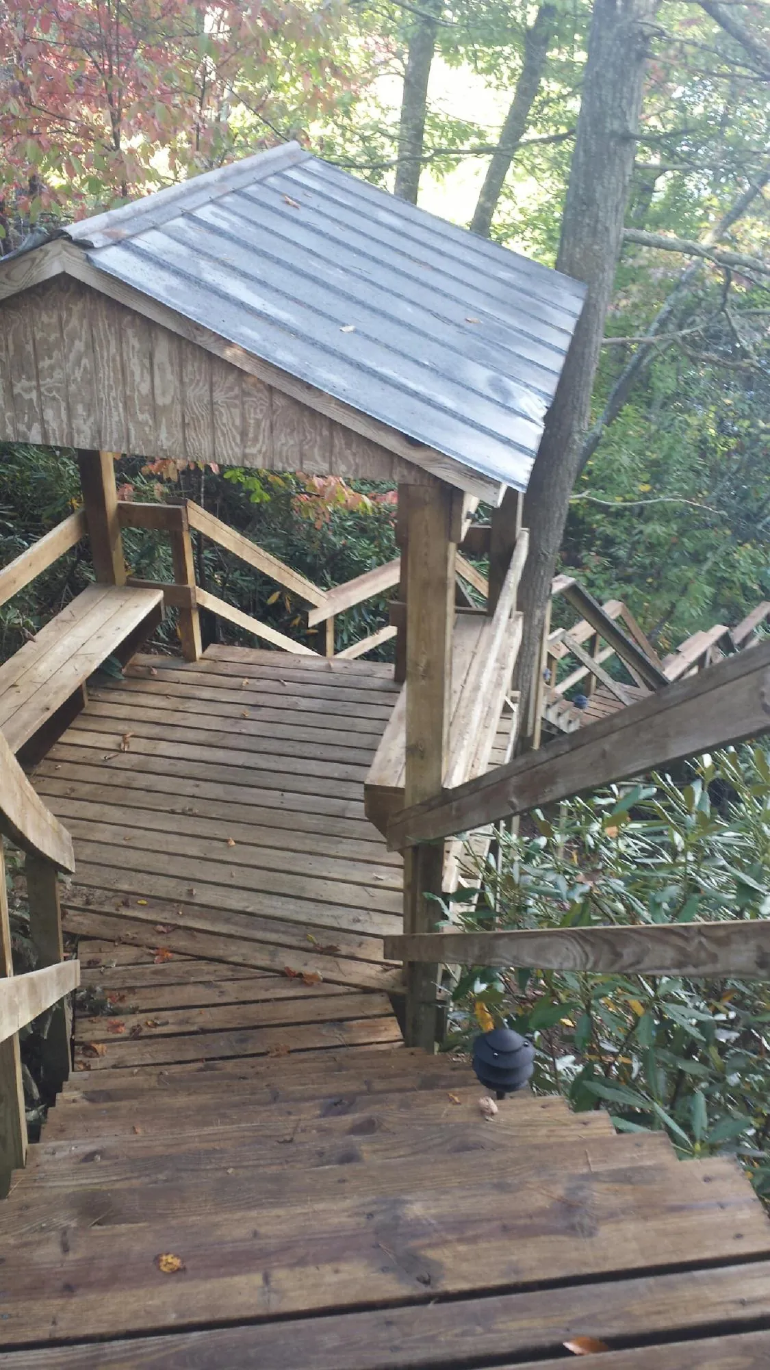 Metal roofed shelter over wooden steps on a wooded walkway — Skylight Repair & Installation work by our crew in Oldhams