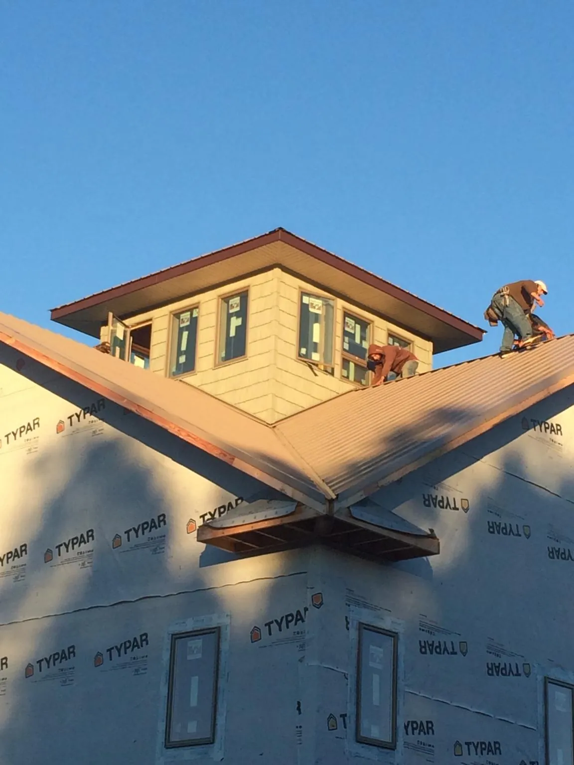 Roofers working around a rooftop cupola on a new metal roof at sunset — Roof Waterproofing in Oldhams by Roofing Brothers